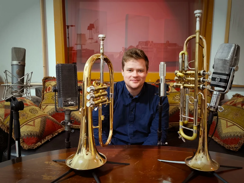 Matej Korbelič mit Flügelhorn und Trompete, umgeben von Bändchen- und Neumann-Mikrofonen im Hot Milk Studio Berlin.